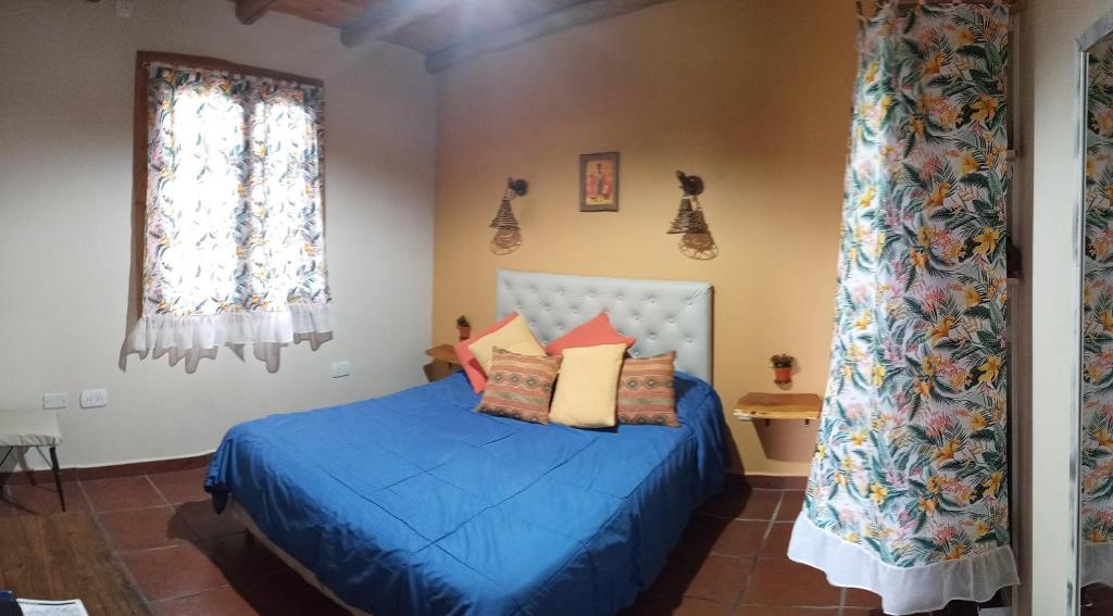 Un dormitorio con una cama azul y una ventana en Cabañas Monika - Alta en Huerta Grande