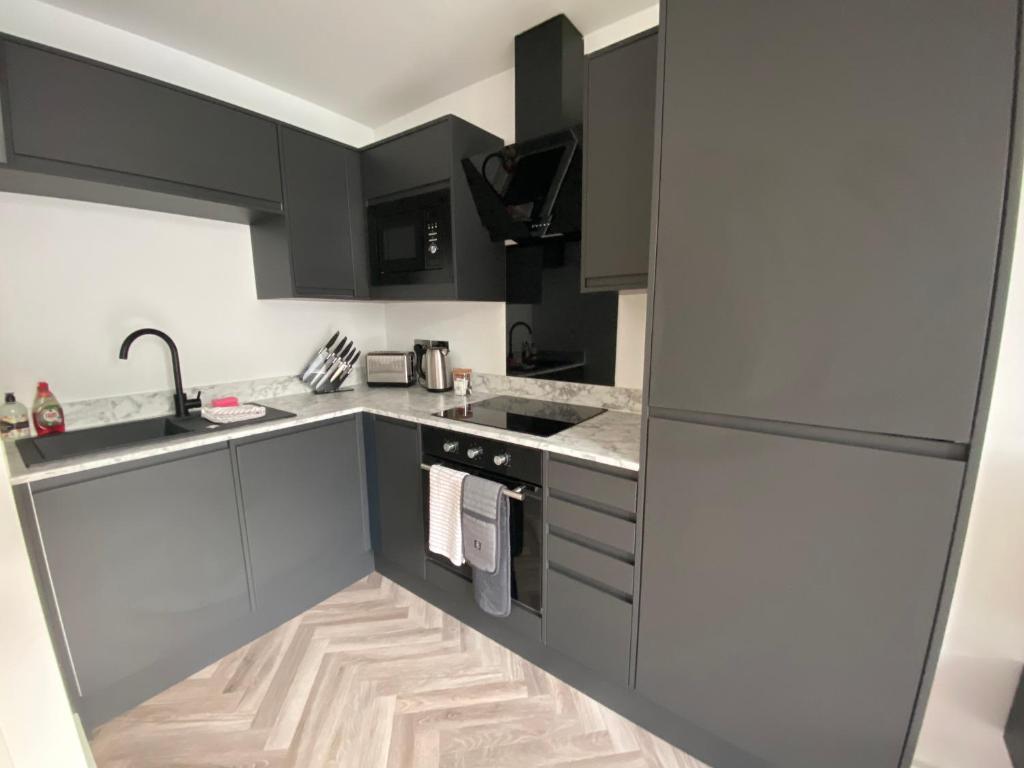 a kitchen with black cabinets and a sink at Stylish Apartments near the sea front at Morecambe in Heysham