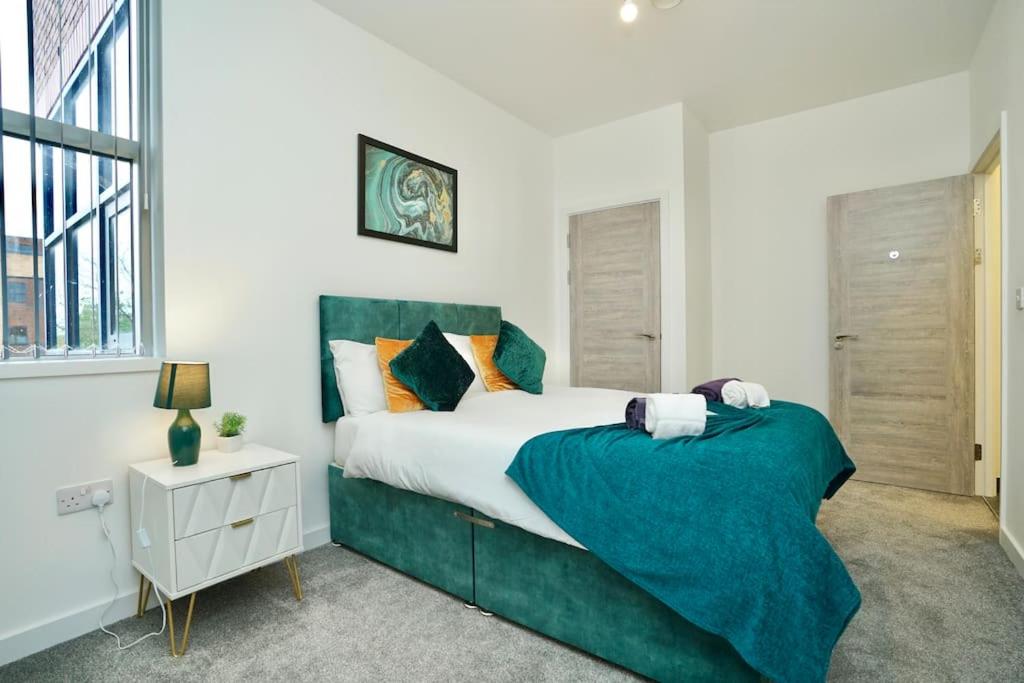 een slaapkamer met een groot bed en een groene deken bij Apartment by DH ApartHotels in Peterborough