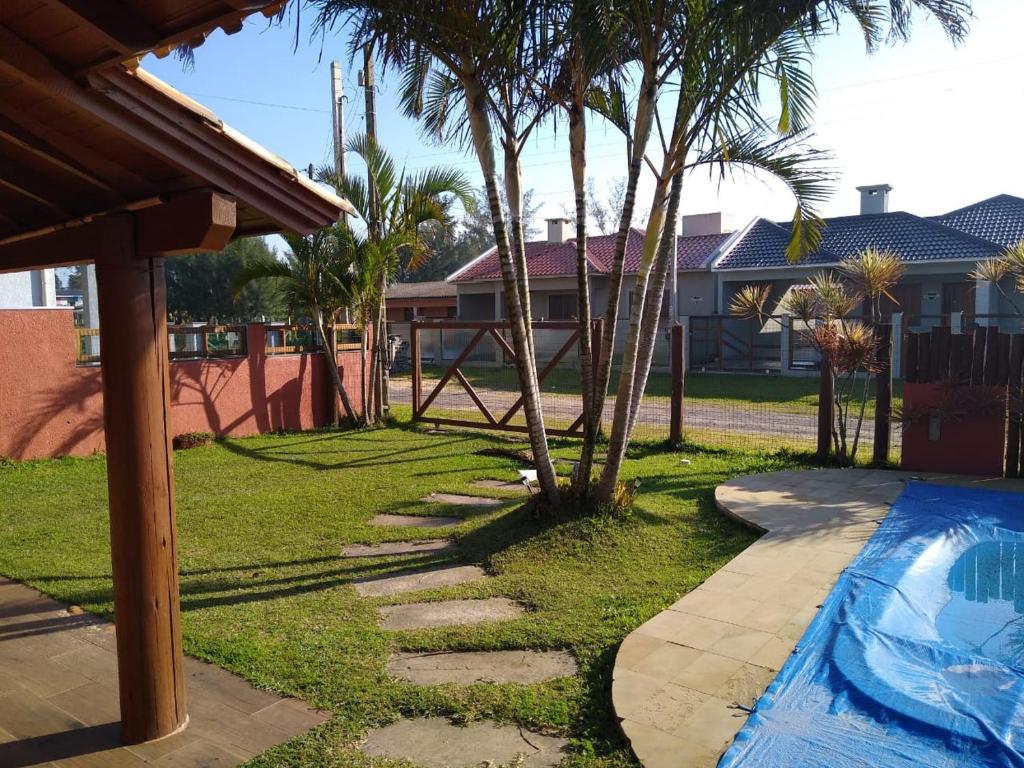 einen Fußweg neben einem Pool mit Palmen in der Unterkunft casa praia in Arroio do Sal