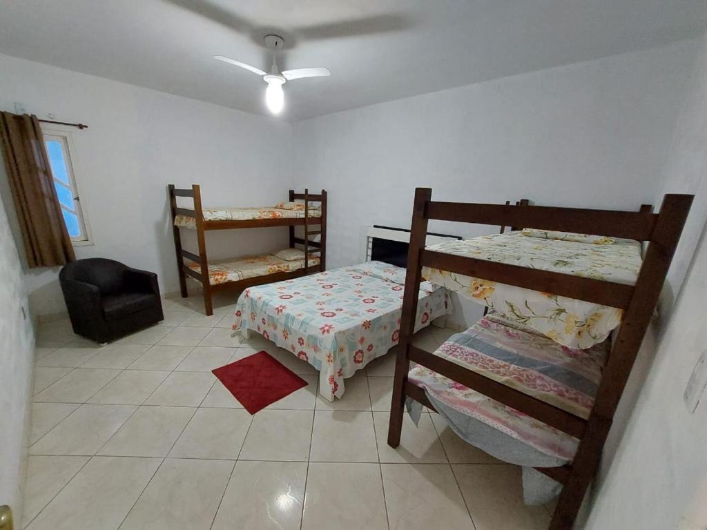 Nacif&Alcantara Suítes في Tamoios: غرفة نوم بسريرين بطابقين وكرسي