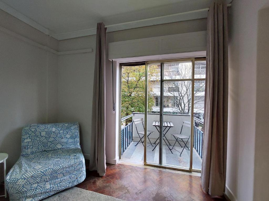 uma sala de estar com uma cadeira e uma porta de vidro deslizante em Lisbon`s best at Campo Pequeno em Lisboa