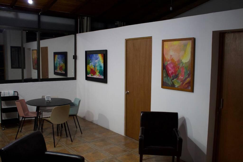 a room with a table and chairs and paintings on the wall at NIce & cozy apt in San José Ins. in Mexico City