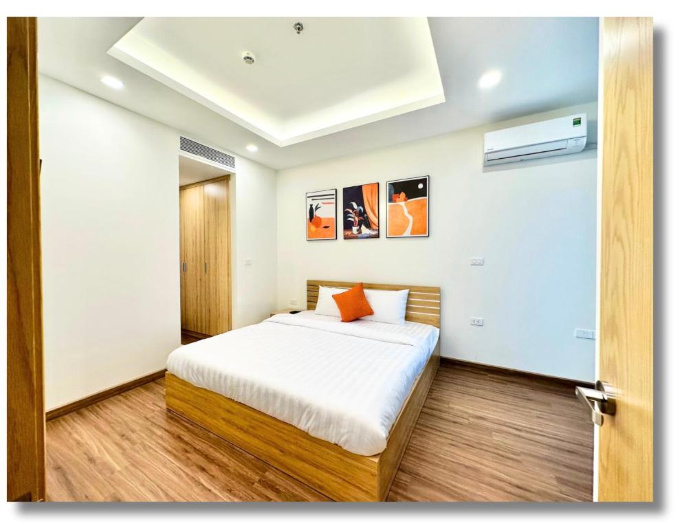 a bedroom with a bed with white sheets and orange pillows at FLC Luxury Apartment Quy Nhon in Quy Nhon