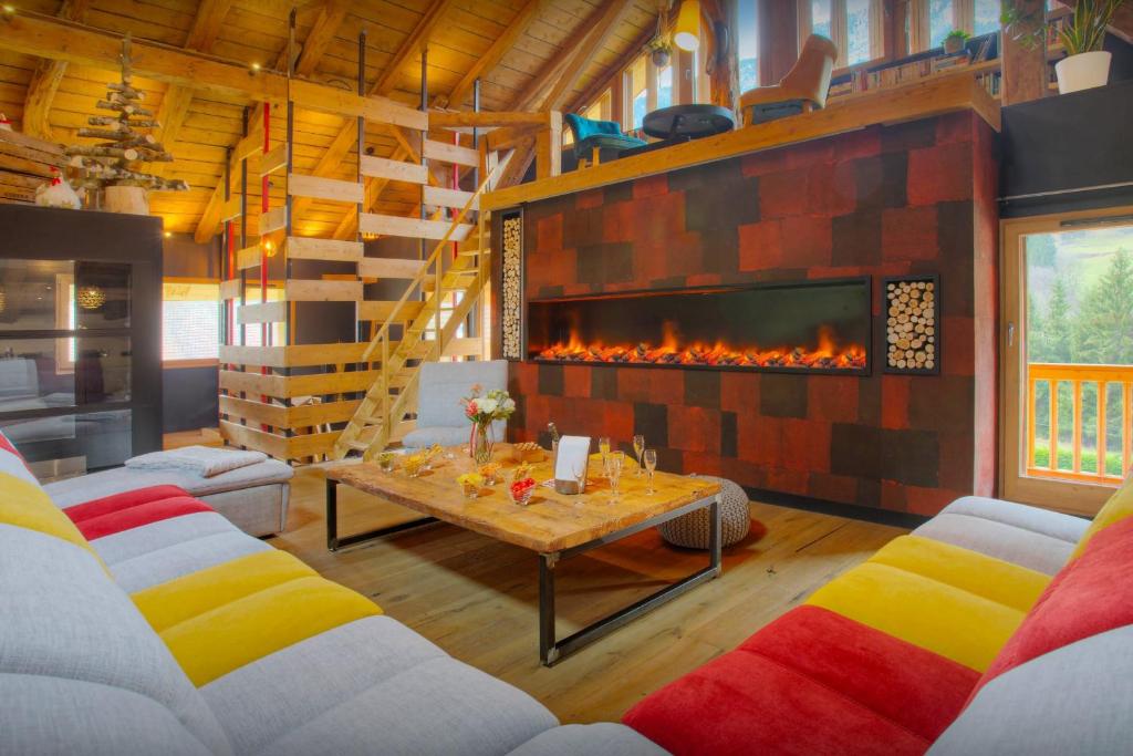 a living room with a fireplace and a table at Chalet 1703 - OVO Network in Le Petit-Bornand-lès-Glières