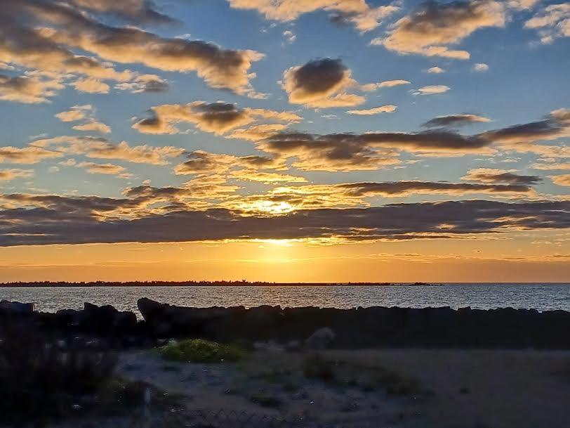 zachód słońca na plaży z wodą i chmurami w obiekcie ARMAREAOVERSEASSUITES w mieście Fiumicino