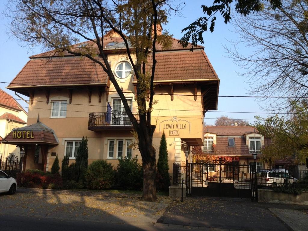 a large house with a tree in front of it at Lévay Villa Hotel in Miskolc