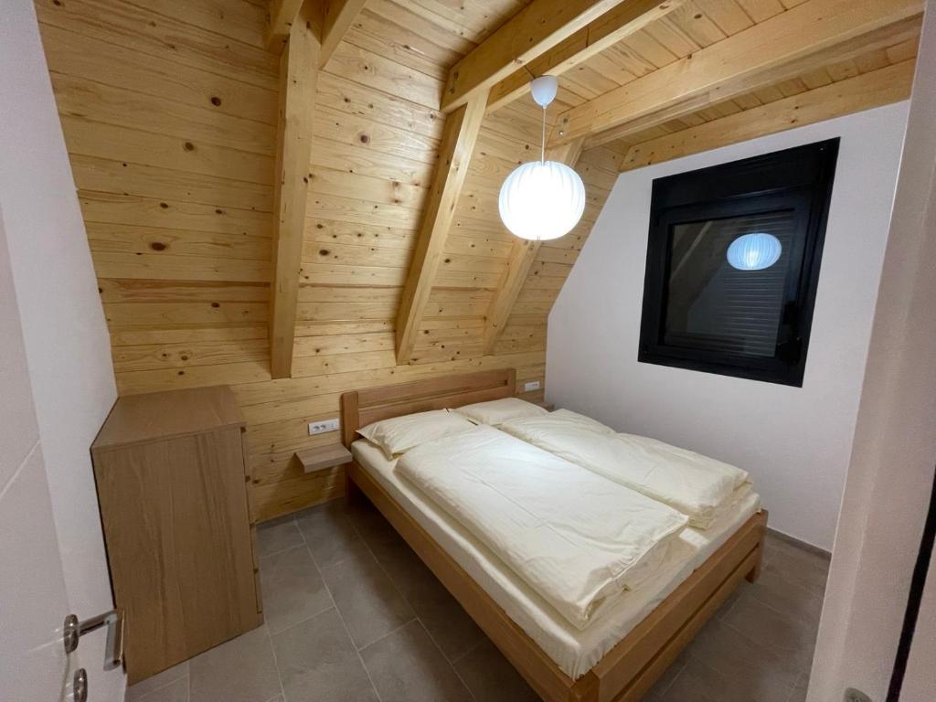 ein kleines Schlafzimmer mit einem Bett in einem Holzzimmer in der Unterkunft KoCHALET Apartment in Crni Vrh