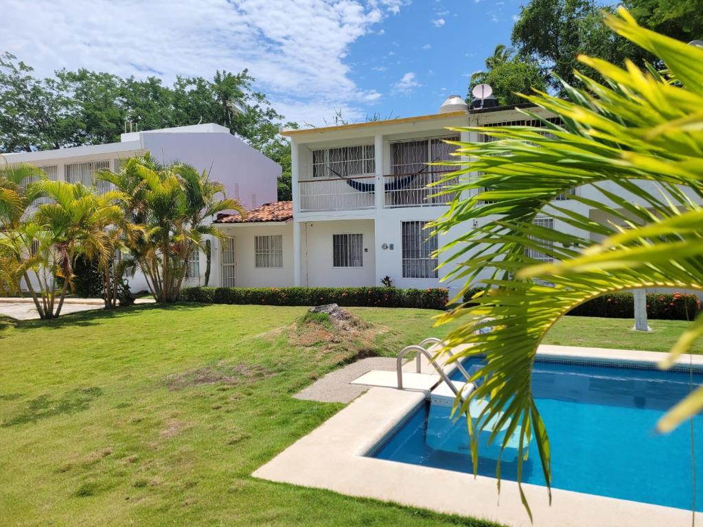 a villa with a swimming pool in front of a building at Casa Amarilla in Zihuatanejo