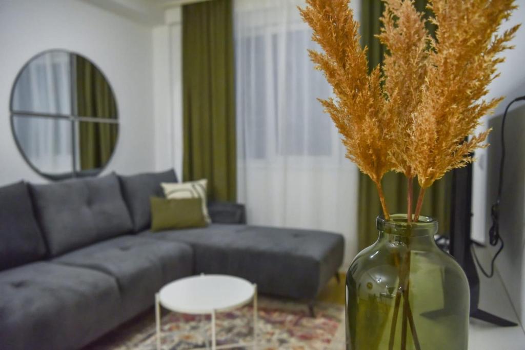 a living room with a couch and a vase with flowers at City centar lux apartman in Zlatibor