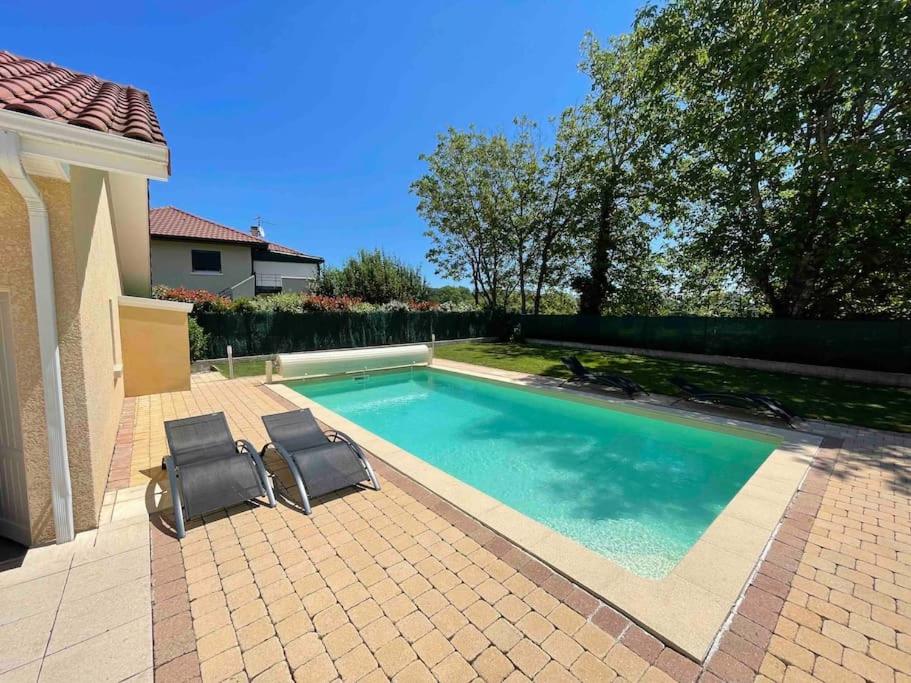 deux chaises assises à côté d'une piscine dans l'établissement Villa piscine proche de Genève et du Jura, à Saint-Genis-Pouilly