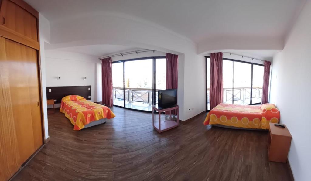 a hotel room with two beds and a television at Hotel Charlie Inn in Iquique