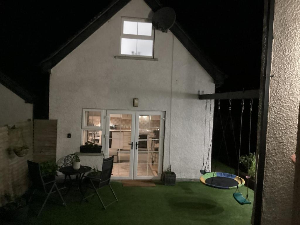 a house with a patio with a table and chairs at Ballinacross Lodge in Foyle Hill