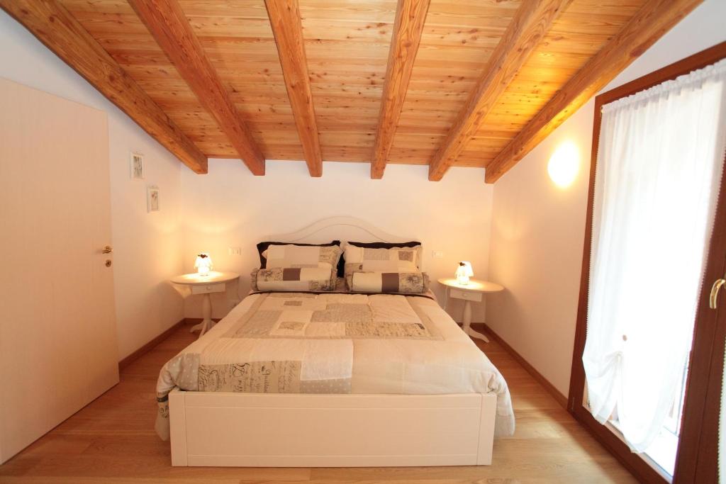 Albergo Diffuso Polcenigo D. Brolo في Polcenigo: غرفة نوم بسرير كبير وسقوف خشبية