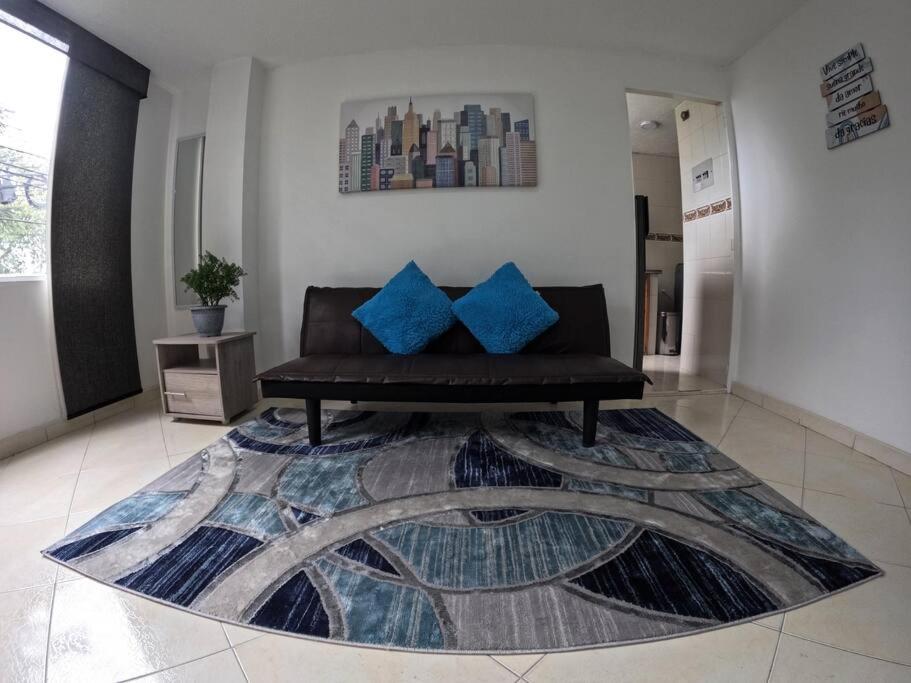 a living room with a black couch and blue pillows at Luminoso y Confortable apt 6 minutos del aeropuerto in Bogotá