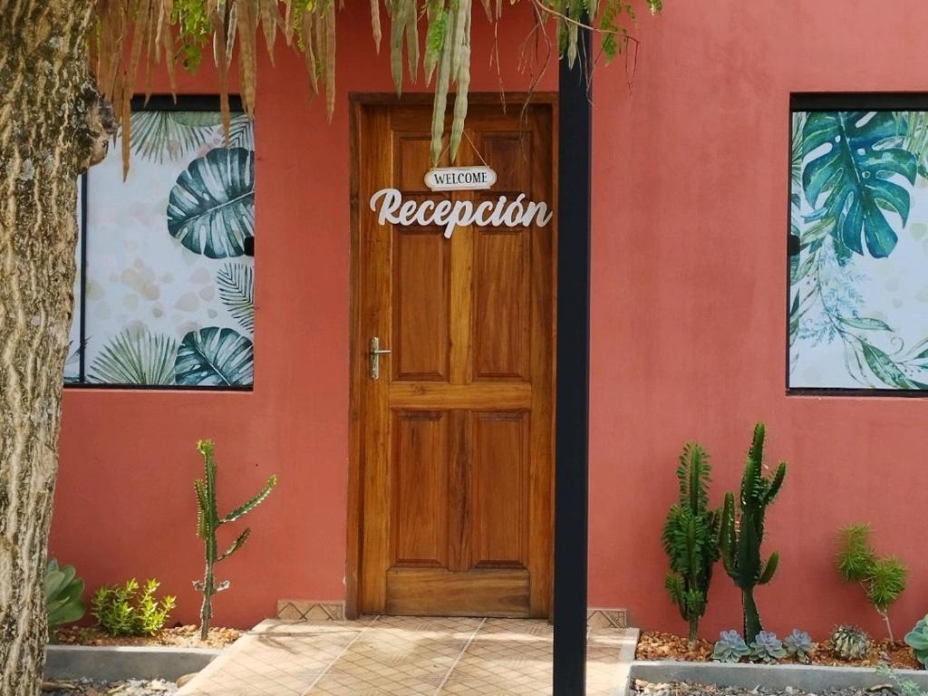 une maison rouge avec une porte en bois munie d'un panneau. dans l'établissement AreGua'i Alojamientos, à Villarrica