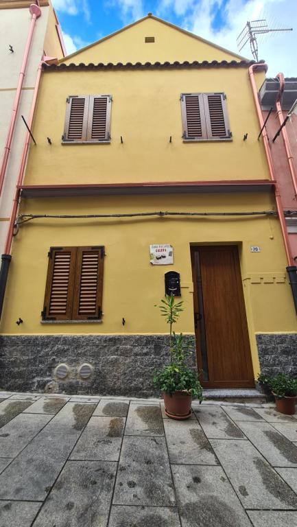 una casa amarilla con dos ventanas y una puerta en Casa vacanze Galena, en Iglesias