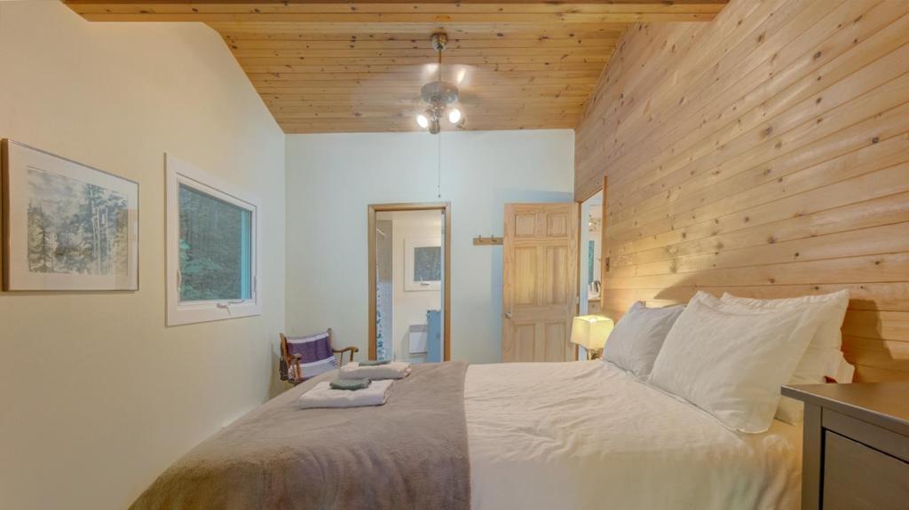 um quarto com uma cama e uma parede de madeira em Chalet dans les arbres. 3 ch. /trees house 3bdr em Lac Sainte-Marie