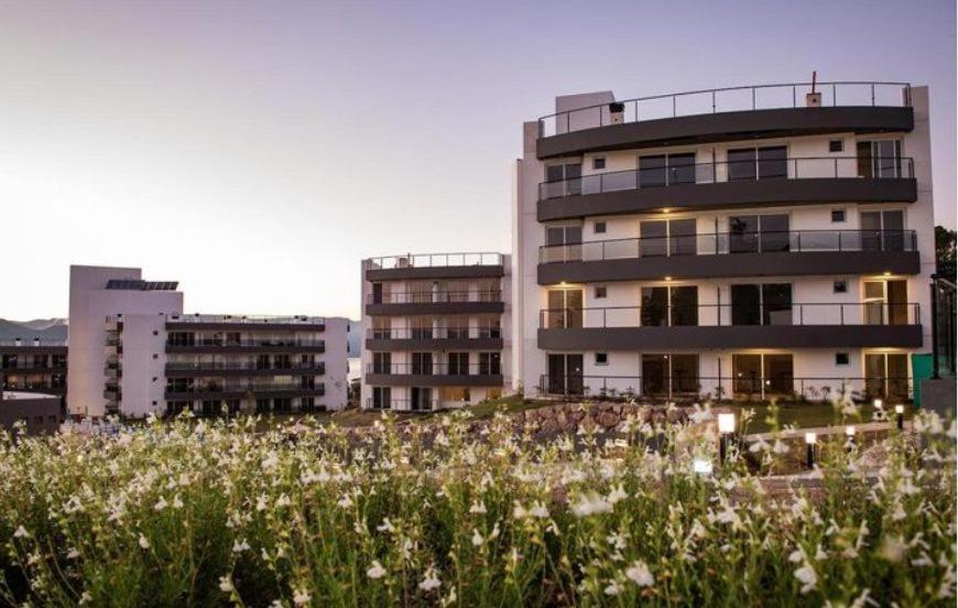 a building with a field of flowers in front of it at Departamento Veneto Village, Parque Siquiman, Carlos Paz in Villa Parque Siquiman