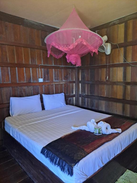 a bed in a wooden room with a pink umbrella at Riverside Bungalow Don Det in Don Det