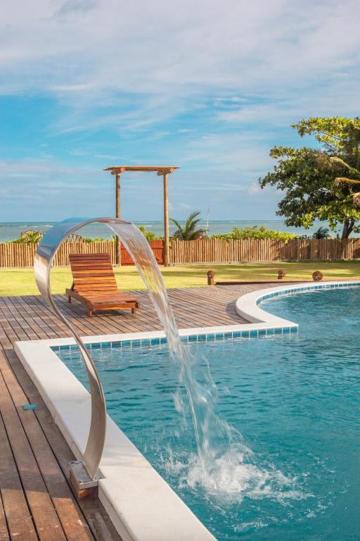 a fountain in a swimming pool with a bench at POUSADA E RESTAURANTE GAROUPA in São Miguel dos Milagres