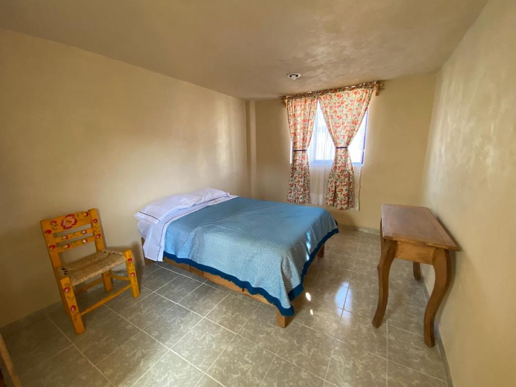 a bedroom with a bed and a table and a chair at Casa Meraki in Ixmiquilpan