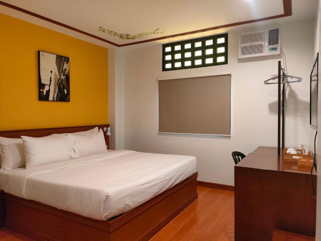 1 dormitorio con cama, escritorio y ventana en LaVie Hotel en Vigan