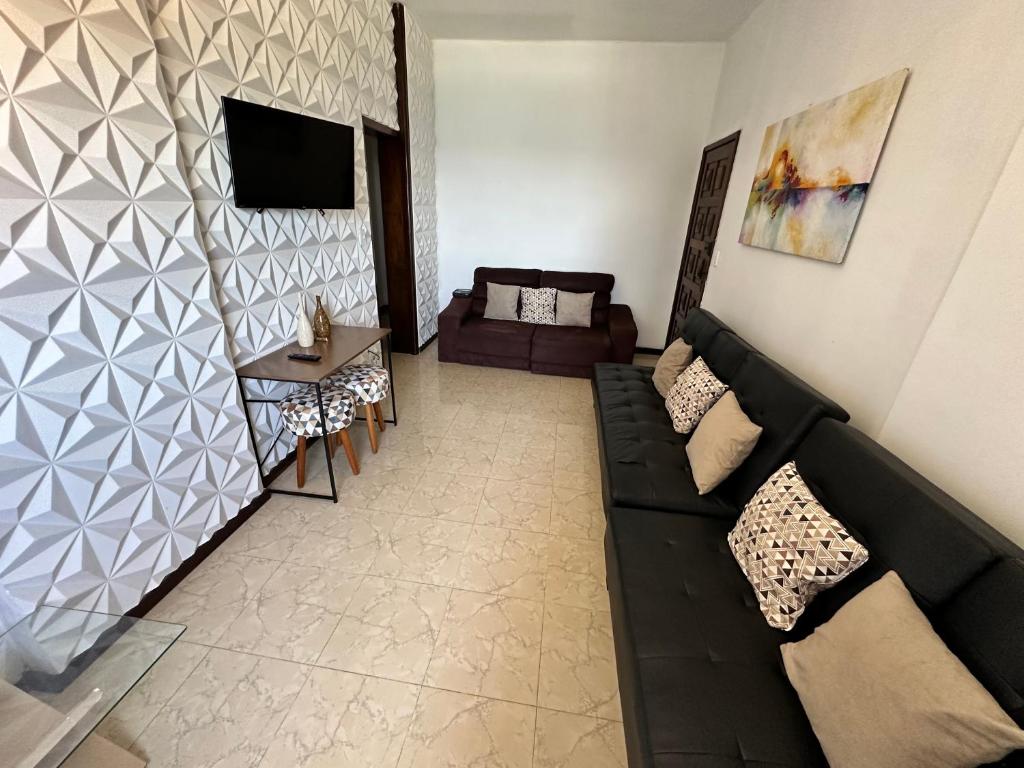 sala de estar con sofá negro y TV en Belíssimo apartamento vista mar deslumbrante na Barra! Direto na praia e no circuito do Carnaval de Salvador., en Salvador