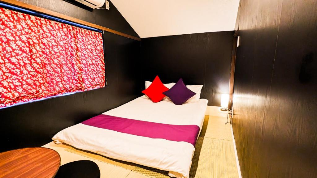 a bedroom with a bed with red and purple pillows at USJ 2 stops, Umeda&Dotonbori 8mins, Ninja Style SV1 in Osaka