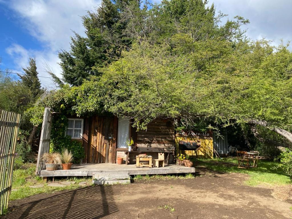 a cabin with a wooden porch under a tree at BAJO EL ÑIRE in San Carlos de Bariloche
