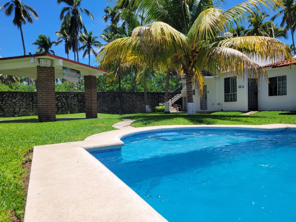 a swimming pool in front of a house with a palm tree at Casa de las Palmas in Zihuatanejo