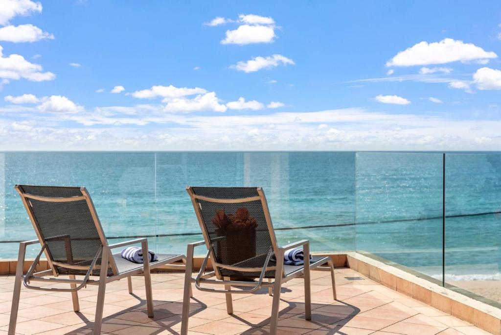 two chairs and a table on a balcony with the ocean at Aqua Shores Penthouse in Mollymook