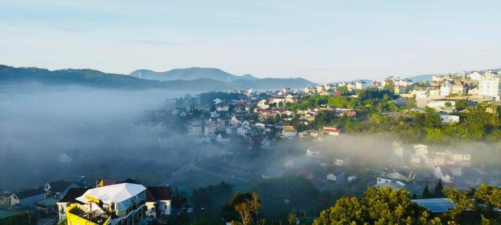 uma cidade no nevoeiro com edifícios e árvores em KND Golden Hills Phúc Đà Lạt em Da Lat