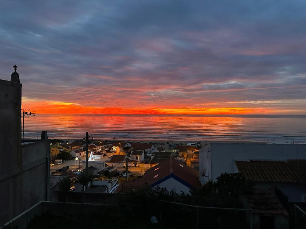 een zonsondergang over de oceaan met een stad en een stad bij FPortugalTours in Sintra