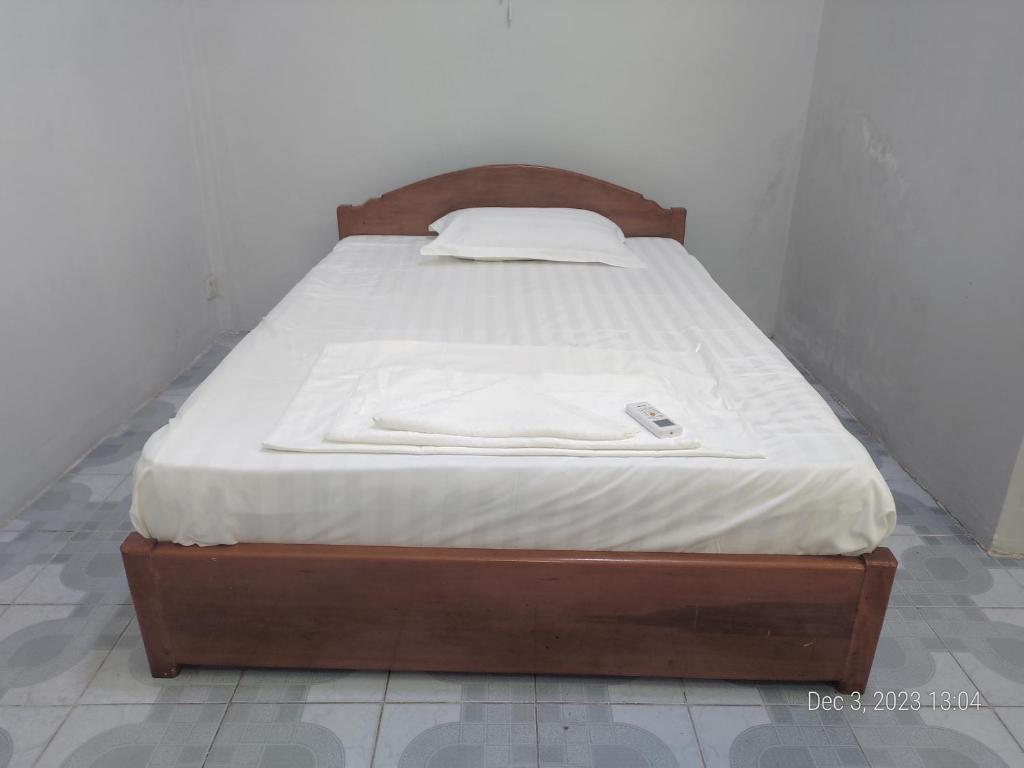 a bed with a wooden frame in a room at Rhythm Bollywood Guesthouse in Phnom Penh