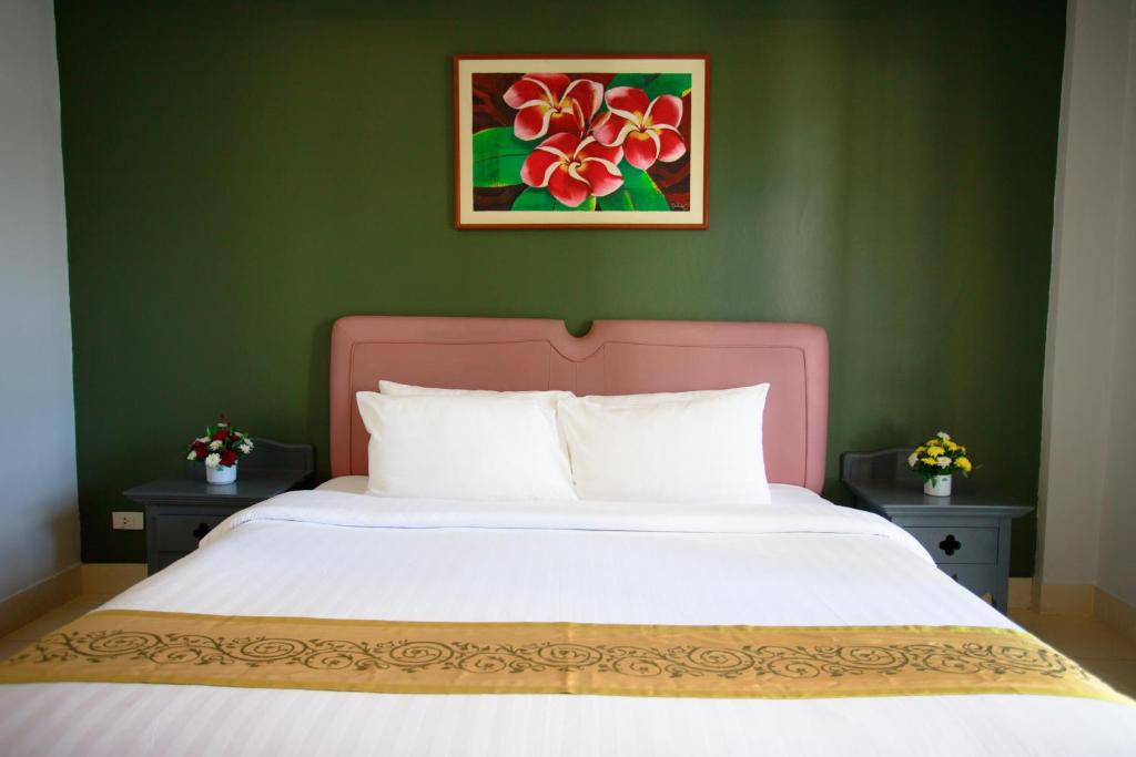 a bed with a pink headboard in a green bedroom at The Corner in Patong Beach