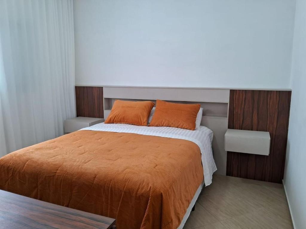 sypialnia z dużym łóżkiem i pomarańczowym kocem w obiekcie Residencial 04 Monte Carlo em São Roque w mieście São Roque