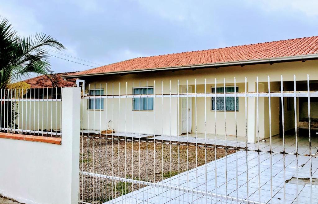 une clôture blanche devant une maison dans l'établissement Linda casa para temporada, 450mts da praia, perto do aero porto, Beto Carreiro, Balneário Camboriú, com amplo terreno na frete e atra, à Navegantes