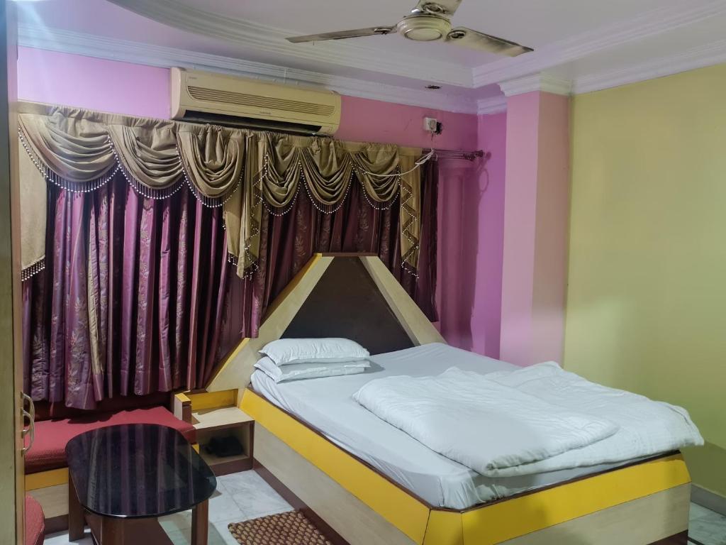 a bed in a room with pink and yellow paint at Hotel Omkar, Tripura in Agartala