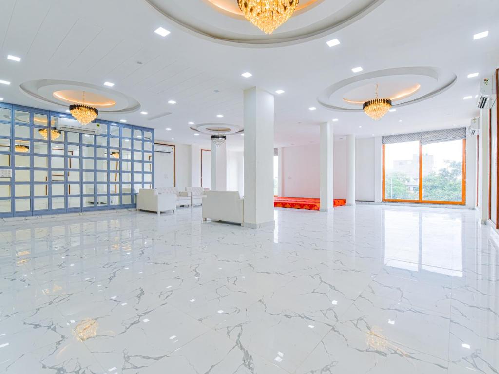 una grande stanza con pavimento in marmo e lampadari di Hotel Vibha Palace a Jaipur