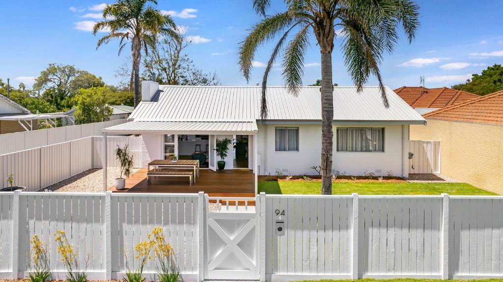 a white fence in front of a house with palm trees at Fairbairn Family Beach Bungalow in Busselton