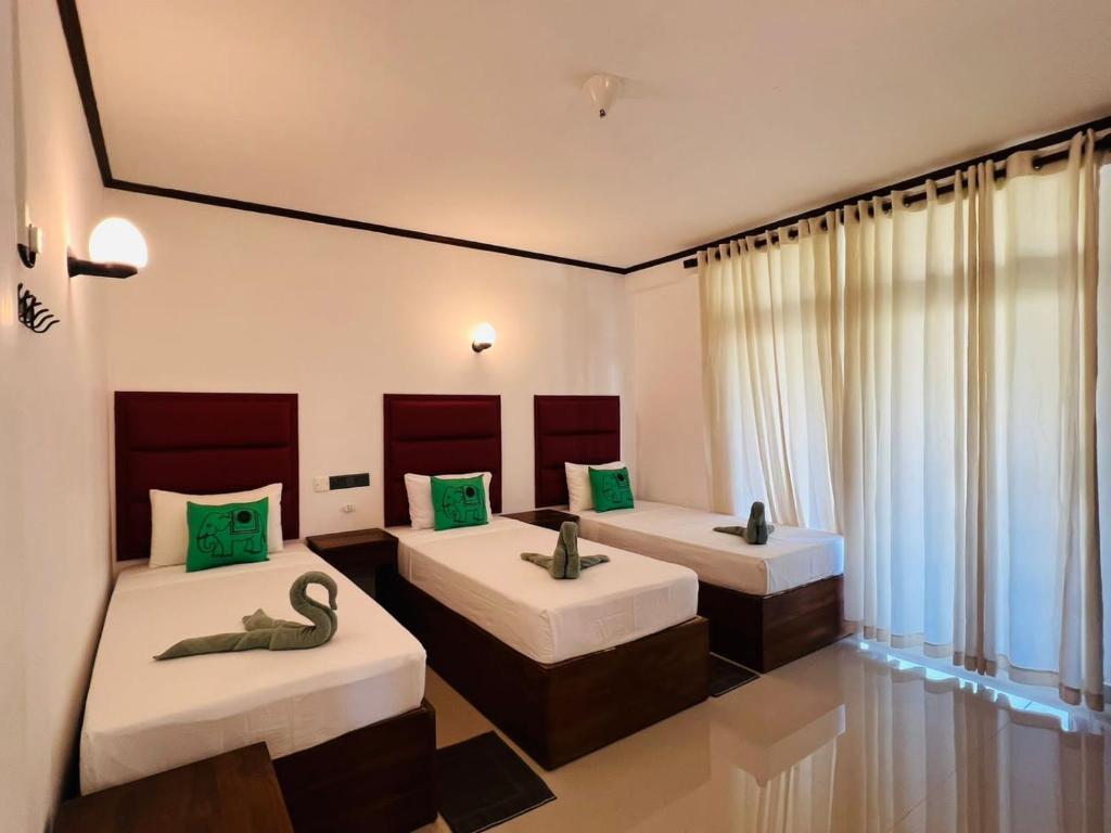 um quarto com 2 camas e almofadas verdes em Lemazone Inn em Mirissa