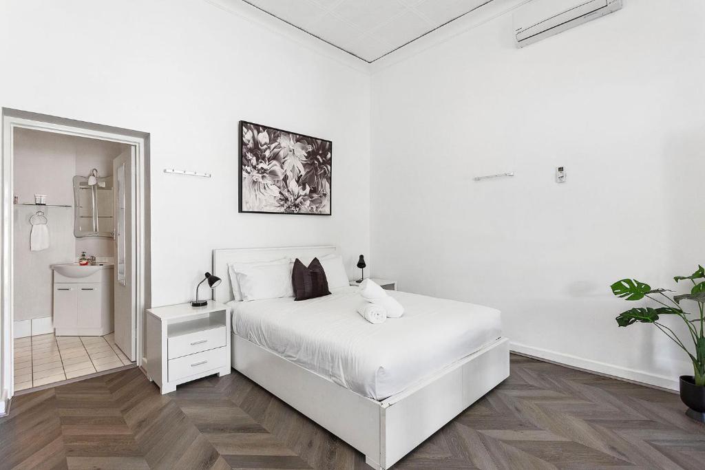 - une chambre blanche avec un lit blanc et un miroir dans l'établissement Stroll To Fremantle's Core Studio Apartment, à Fremantle
