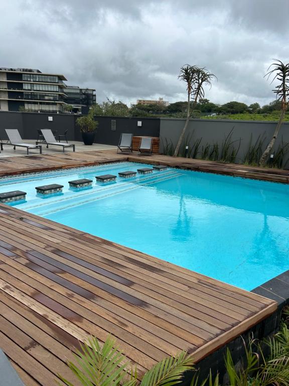 - une piscine avec une terrasse en bois à côté d'un bâtiment dans l'établissement Flat in umhlanga, à Durban