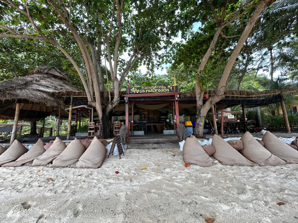 Apsara & Dragon’s Supra Wellness Resort في بان تاي: صف من الوسائد البيضاء على الرمال على الشاطئ