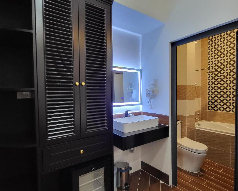 ein Badezimmer mit einem Waschbecken, einem WC und einem Spiegel in der Unterkunft RUBY HOTEL Vĩnh Long in Vĩnh Long