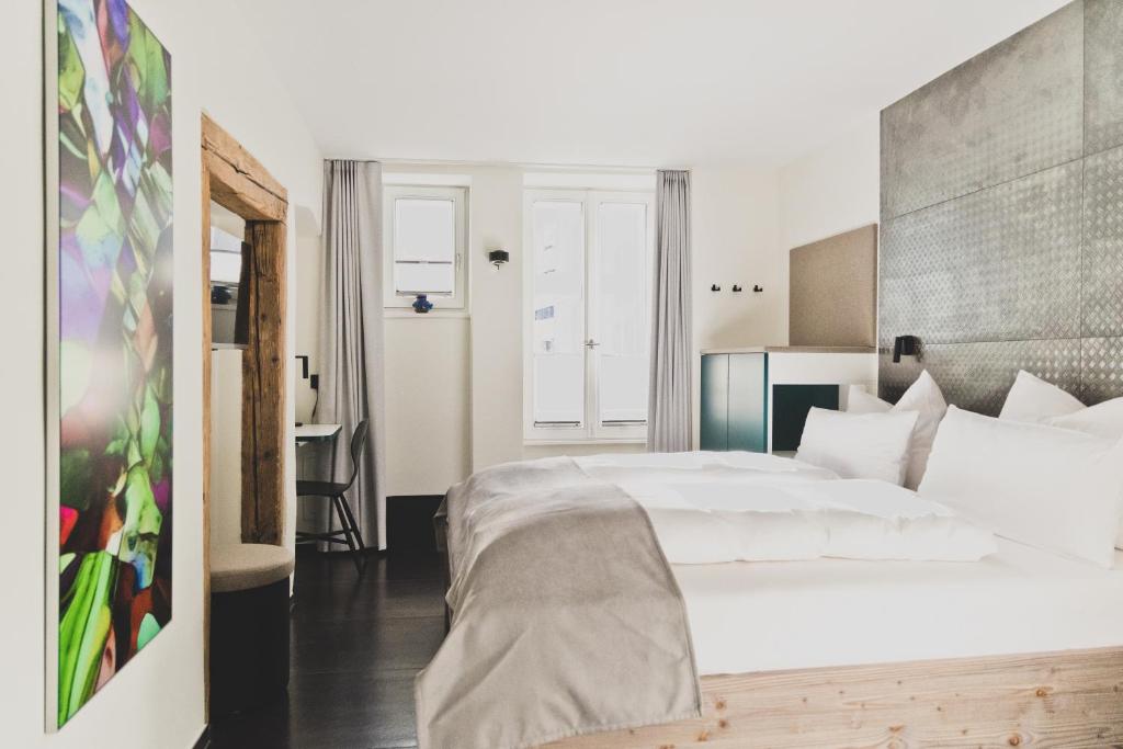 a bedroom with a large white bed and a desk at HOTEL BLAUE ROSE -digital check in- in Feldkirch