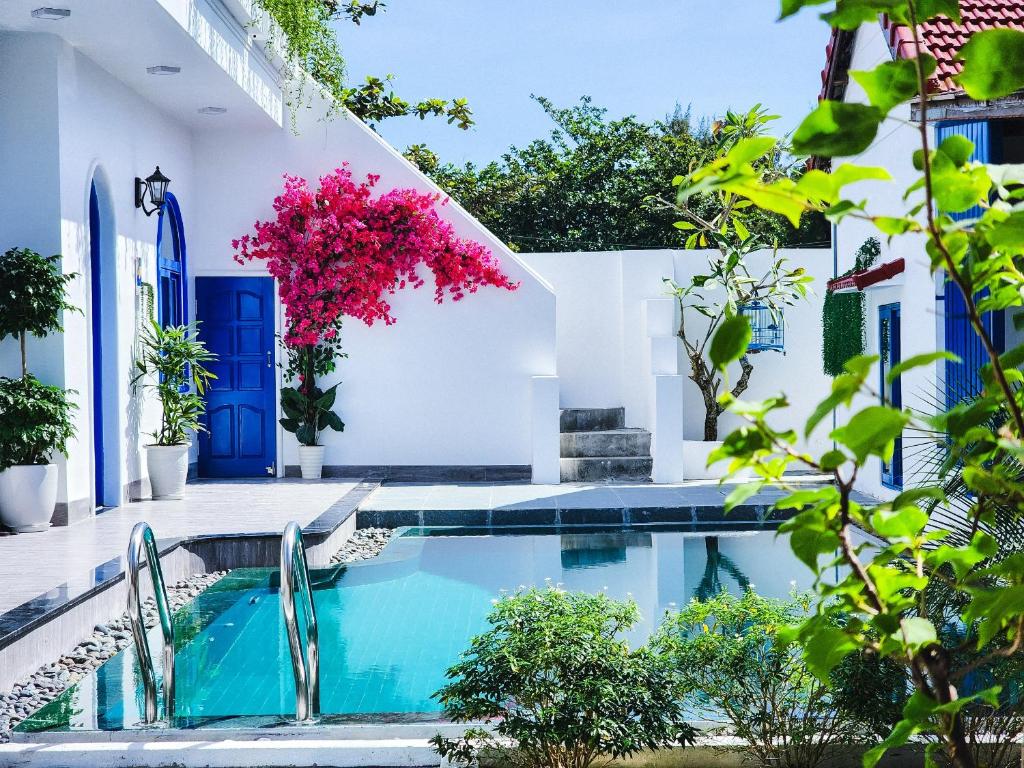 una piscina en una casa con puertas y plantas azules en Dragon Sea Homestay, en Hoi An