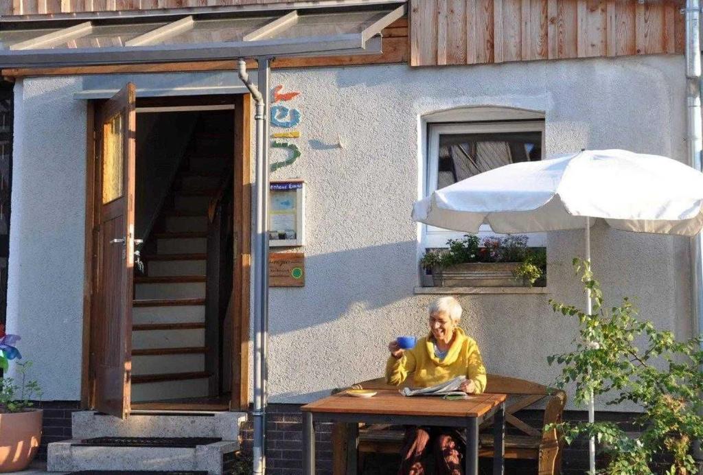 a woman sitting at a table in front of a house at Ferienhaus EMMA in Kleinern