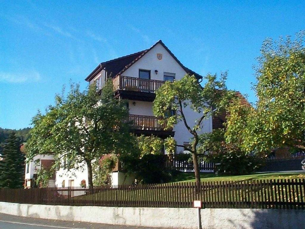 a white house with a balcony and a fence at Haus Bergblick in Bringhausen